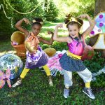 Two young dancers posing in a woodlands scene with disco balls and a sparkly mushroom, getting ready for a fun dance activity!